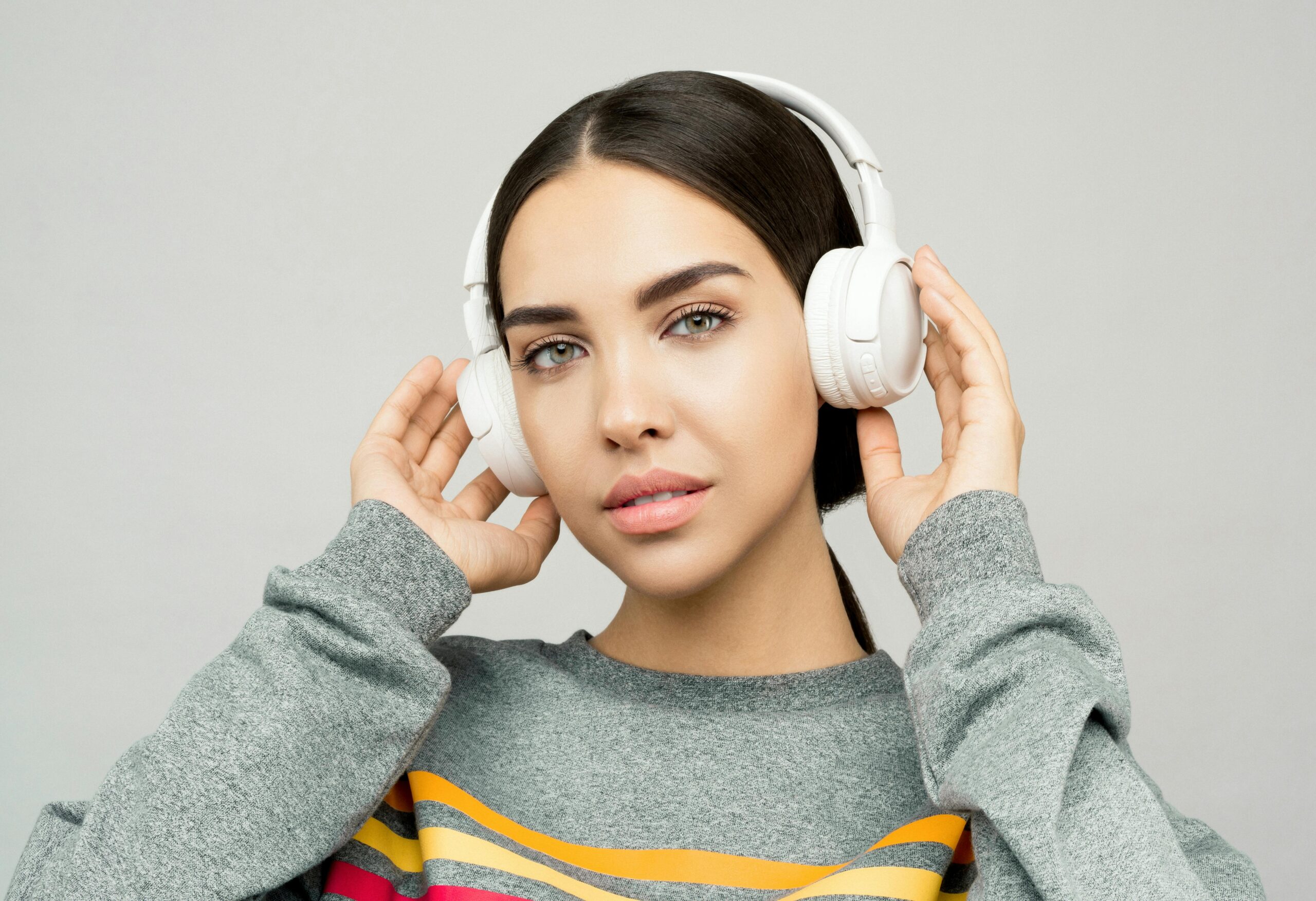 Portrait of a young woman wearing headphones, enjoying music indoors with a casual expression.